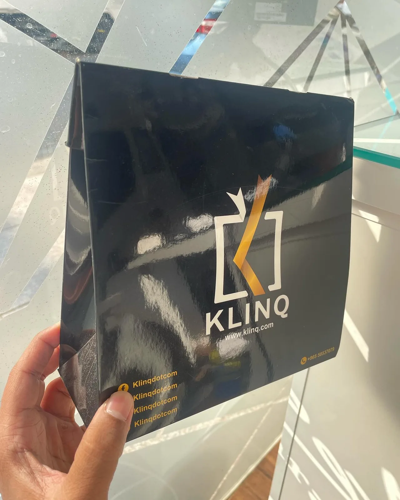 Black paper bag with printed logo, hand-held